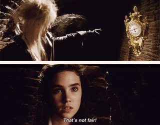 Jareth points smugly at a golden floating clock and sends the hands spinning round. Sarah complains "That's not fair!"